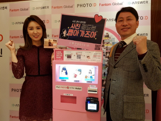 팬텀글로벌(대표 김정주)이 31일 서울 소공동 웨스틴조선호텔에서 기자간담회를 갖고 디앤써(대표이사 정해진)와 공동으로 개발한 동영상 사진 인화기 '포토디(PHOTO:D)'를 선보였다. 포토디는 앞으로 영어, 일본어, 중국어 버전으로 변환해 해외로 수출할 계획이다. 팬텀글로벌 김정주 대표(오른쪽)와 포토디 모델 최예빈 아나운서가 포토디 옆에서 기념촬영을 하고 있다. 팬텀글로벌 제공